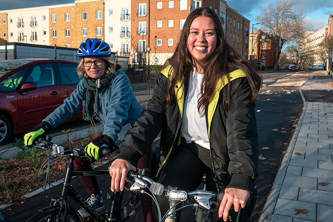 Two cyclists on cycle path smiling