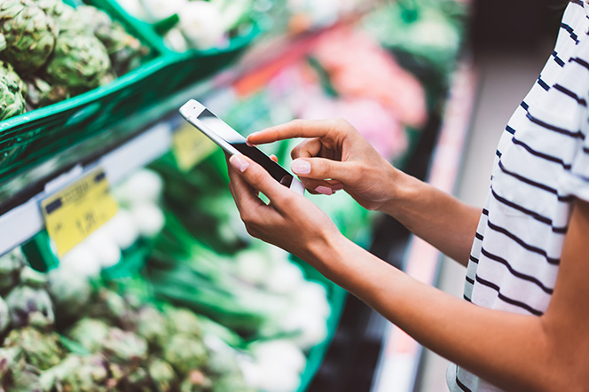 Lady shopping in local market store and checking her phone