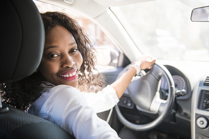 Lady sat in car drivers seat looking over shoulder at passenger