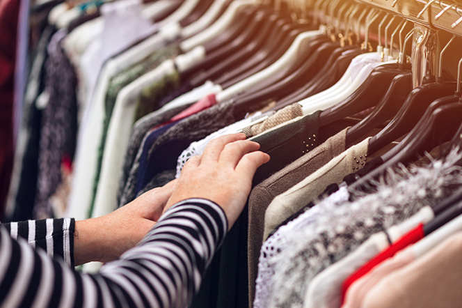 Searching through second hand clothes rack