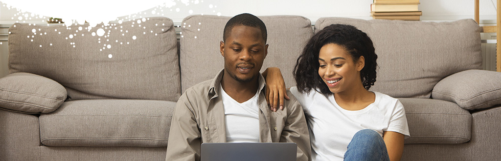 Couple sat on floor with laptop