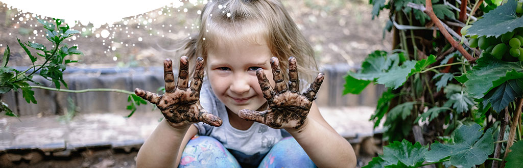 Young child showing muddy hands in the garden