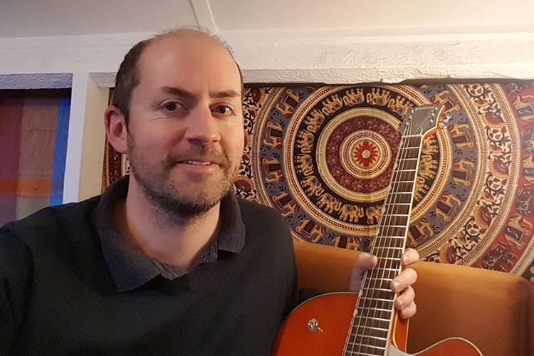 Andy in his house sat with his Guitar